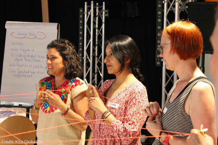 Workshop-Teilnehmende halten einen Faden in der Hand, der ein Netzwerk symbolisiert