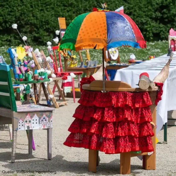 Viel bunt gestaltete Stühle stehen in einem Park an einem Tisch